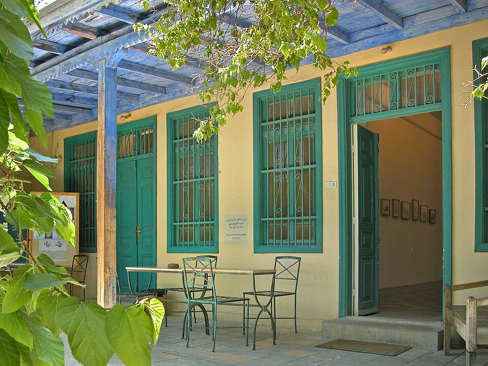 A leafy terrace and turquoise doors at Darat al Funun